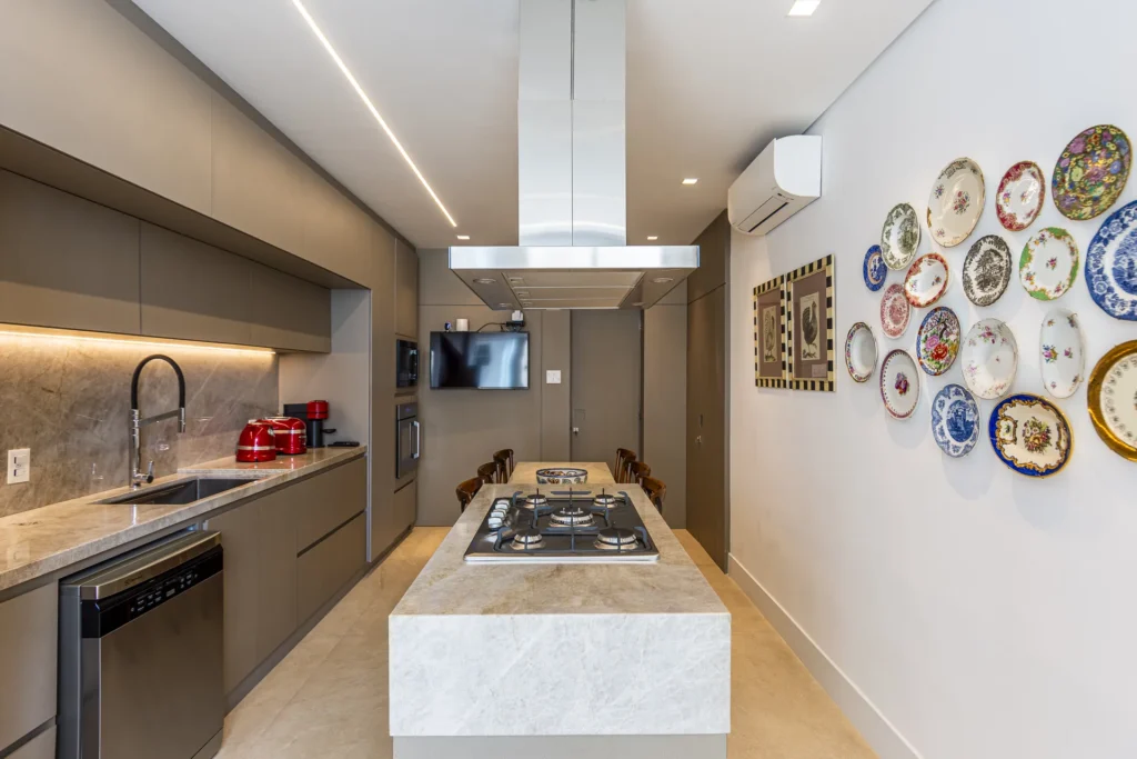 Cozinha com ilha em pedra, cooktop e coifa ilha, marcenaria sob medida