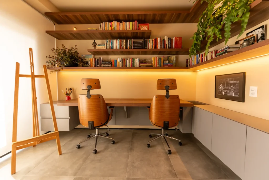 Home office planejado com bancada em madeira, prateleiras e iluminação LED