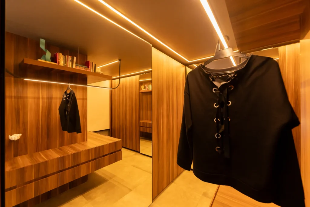 Closet planejado em madeira com nicho, gavetas e iluminação