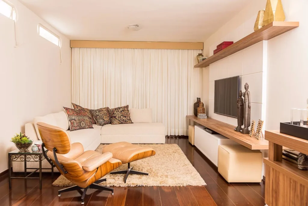 Living com painel planejado, rack branco e prateleiras amadeiradas